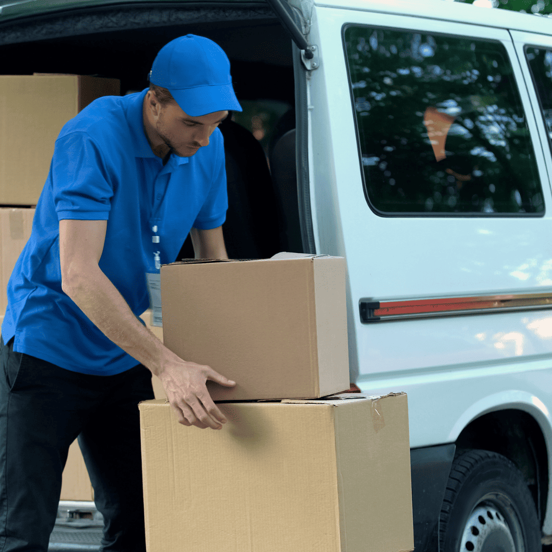 delivery man in blue unloading boxes of goods from van