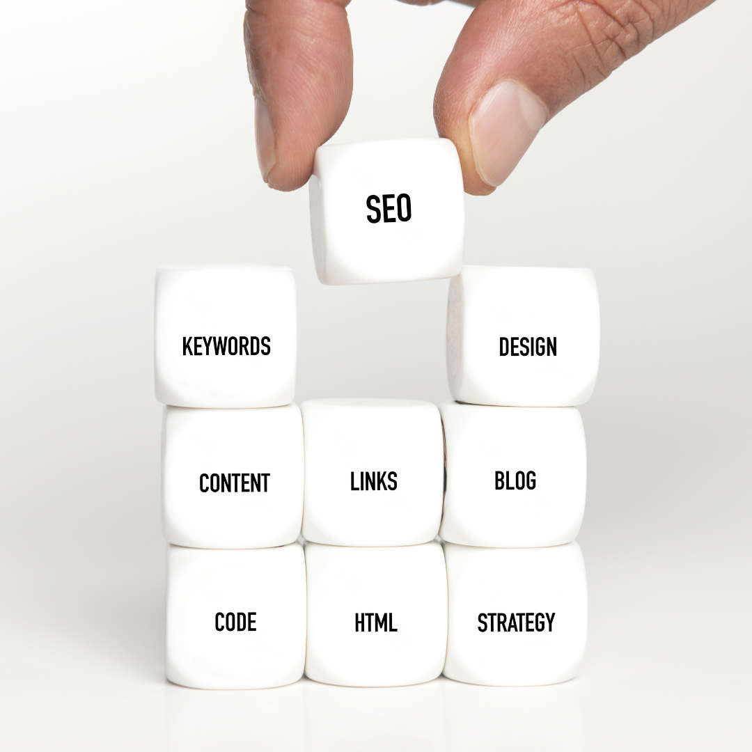 fingers placing a die with the words SEO on it on top of other dice that have seo elements written on them.