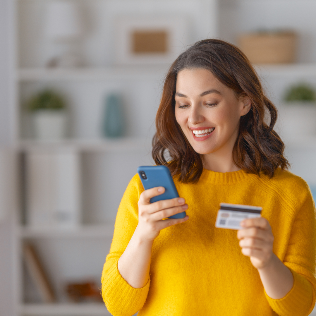 woman holding a phone and her credit card, shopping using BigCommerce BOPIS