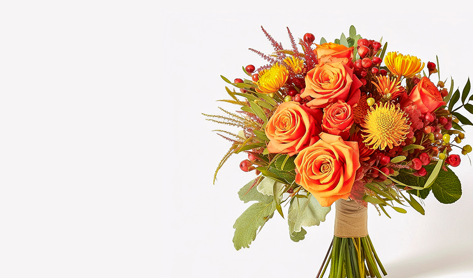 Nebula Eco banner featuring bright autumn bouquet of orange roses, yellow blooms, and red berries wrapped at the stems, displayed against a clean white backdrop.
